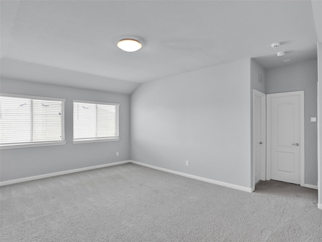 unfurnished room with light carpet and lofted ceiling