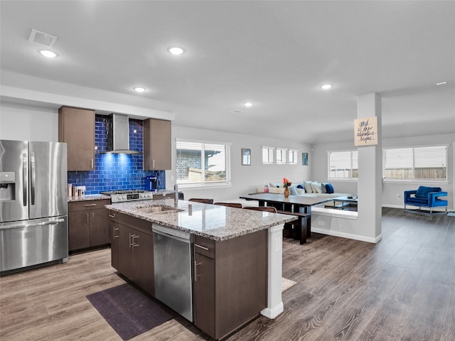 kitchen featuring hardwood / wood-style floors, stainless steel appliances, a center island with sink, and sink