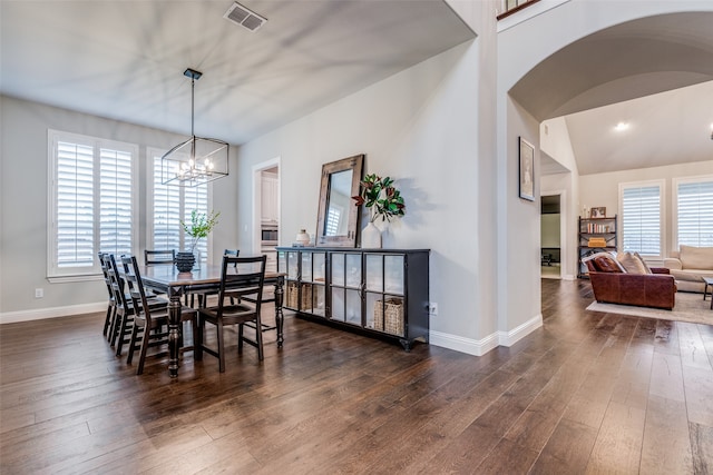 dining space with dark wood-type flooring, vaulted ceiling, and a notable chandelier