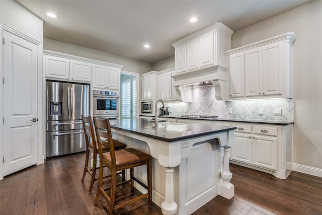 kitchen featuring a kitchen bar, appliances with stainless steel finishes, a kitchen island with sink, sink, and white cabinetry