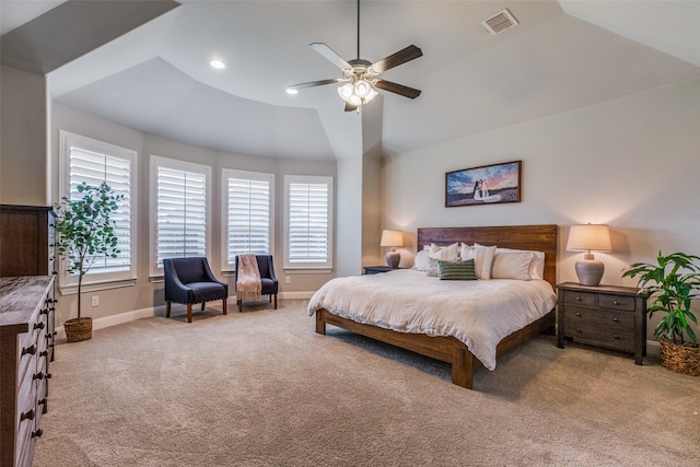 carpeted bedroom with a tray ceiling, vaulted ceiling, and ceiling fan