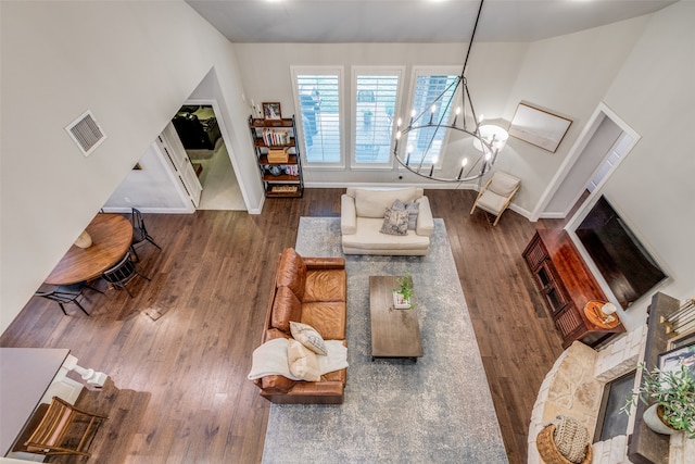 living room featuring a fireplace, an inviting chandelier, and dark wood-type flooring