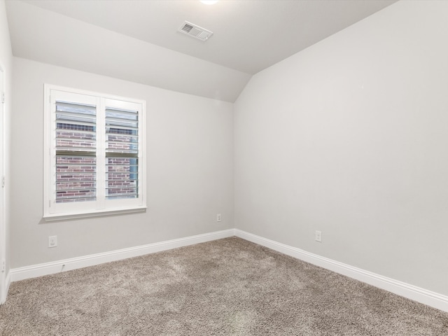 carpeted spare room with vaulted ceiling