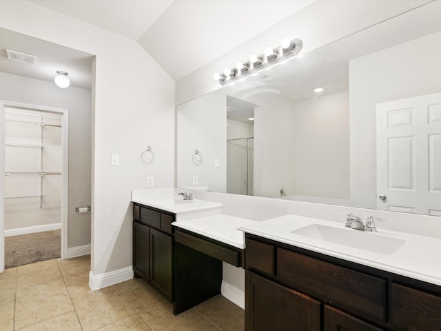 bathroom with vanity, a shower with door, tile patterned floors, and vaulted ceiling