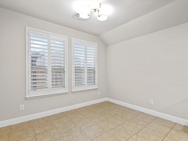 spare room with light tile patterned flooring, lofted ceiling, and a healthy amount of sunlight