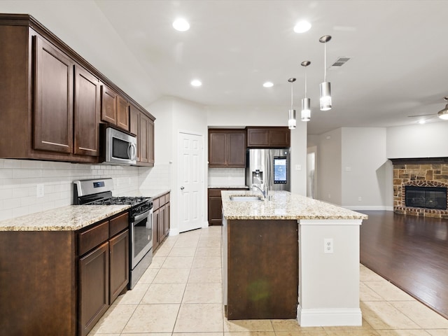 kitchen with light hardwood / wood-style flooring, appliances with stainless steel finishes, light stone counters, and hanging light fixtures