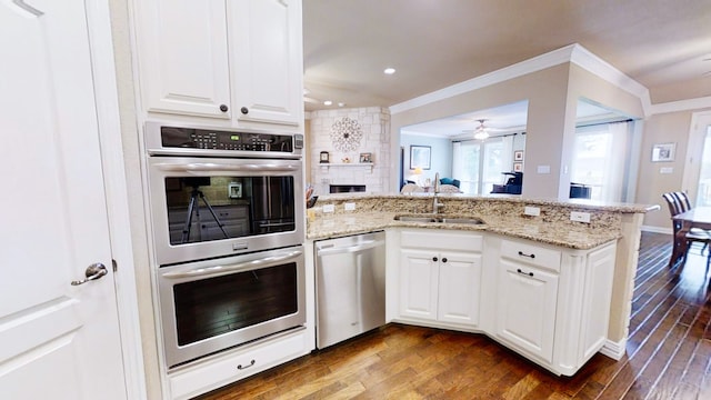 kitchen with stainless steel appliances, white cabinetry, a sink, wood finished floors, and a peninsula