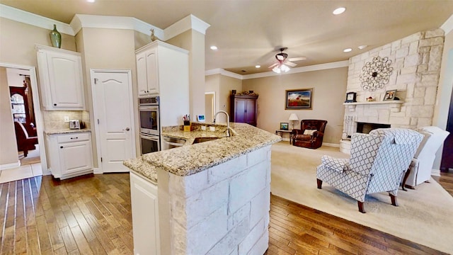 kitchen featuring open floor plan, stainless steel appliances, light stone counters, and white cabinetry