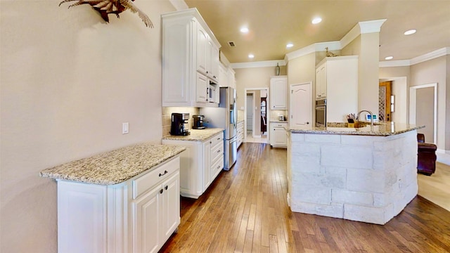 kitchen featuring light wood finished floors, white cabinets, light stone counters, a peninsula, and stainless steel appliances