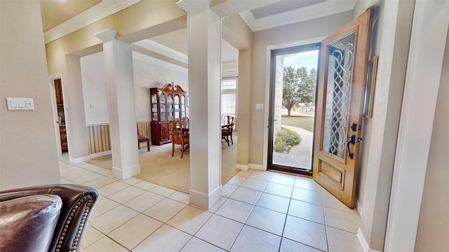 foyer entrance with crown molding, light tile patterned flooring, and decorative columns