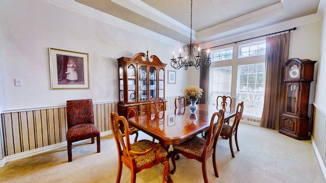 dining space featuring light carpet, an inviting chandelier, a raised ceiling, and wainscoting