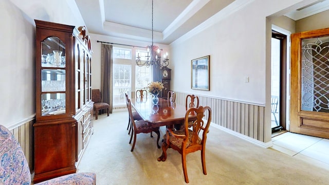 dining area featuring light carpet, wainscoting, a raised ceiling, and an inviting chandelier