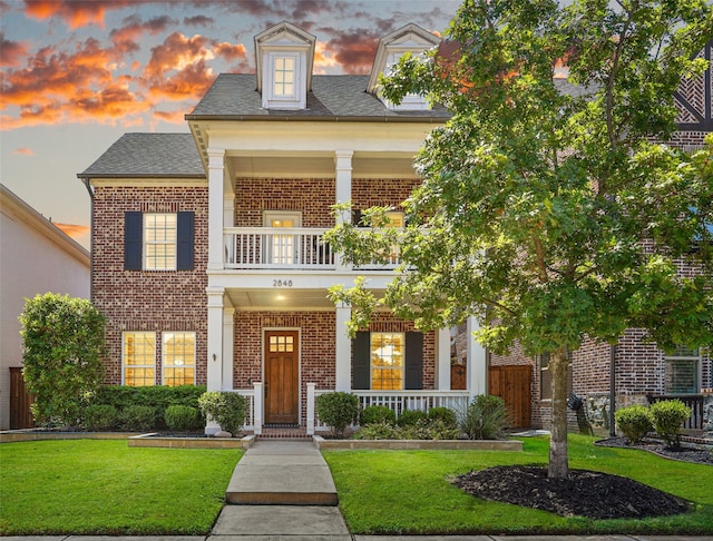 view of front of house featuring a porch, a balcony, and a yard