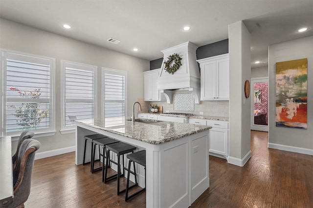 kitchen featuring dark hardwood / wood-style floors, sink, a center island with sink, and white cabinets