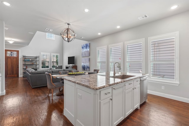 kitchen with sink, light stone counters, a kitchen island with sink, white cabinets, and dark hardwood / wood-style flooring