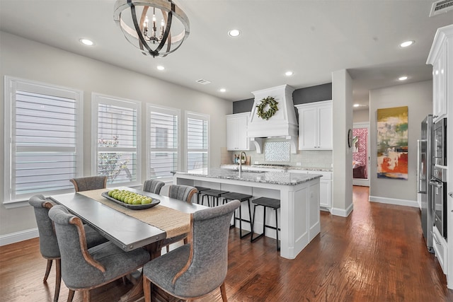 dining room with dark wood-type flooring, sink, and a notable chandelier