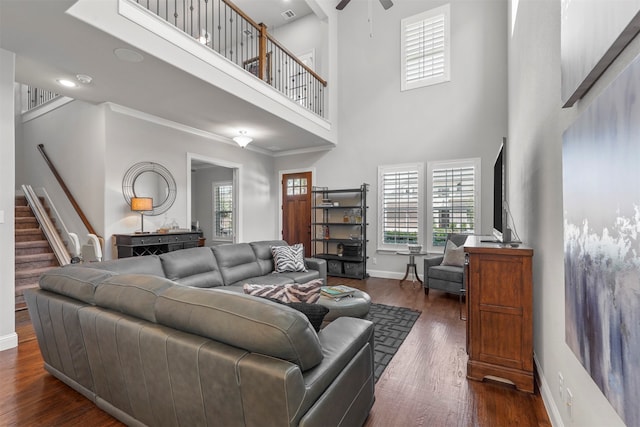 living room featuring dark hardwood / wood-style flooring, ceiling fan, and a towering ceiling