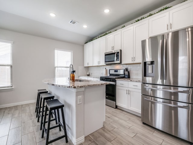 kitchen with a kitchen island with sink, stainless steel appliances, sink, and plenty of natural light