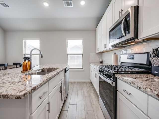 kitchen featuring plenty of natural light, a kitchen island with sink, sink, and stainless steel appliances