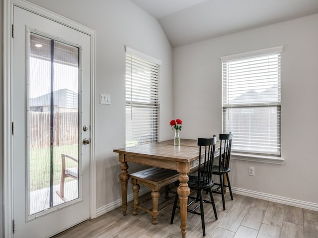 dining area featuring plenty of natural light, light hardwood / wood-style floors, and vaulted ceiling