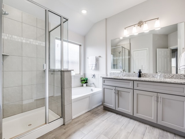 bathroom with vanity, shower with separate bathtub, vaulted ceiling, and hardwood / wood-style flooring