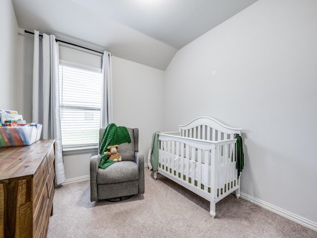 bedroom with a crib, light carpet, and vaulted ceiling