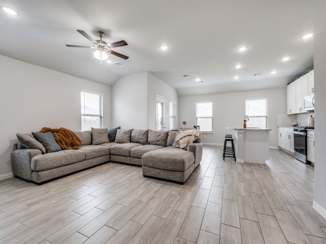 living room featuring light hardwood / wood-style floors, ceiling fan, plenty of natural light, and lofted ceiling