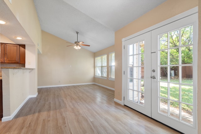 doorway with lofted ceiling, french doors, light hardwood / wood-style floors, and plenty of natural light