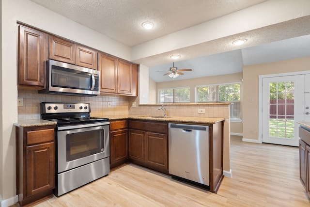 kitchen with kitchen peninsula, stainless steel appliances, lofted ceiling, and plenty of natural light