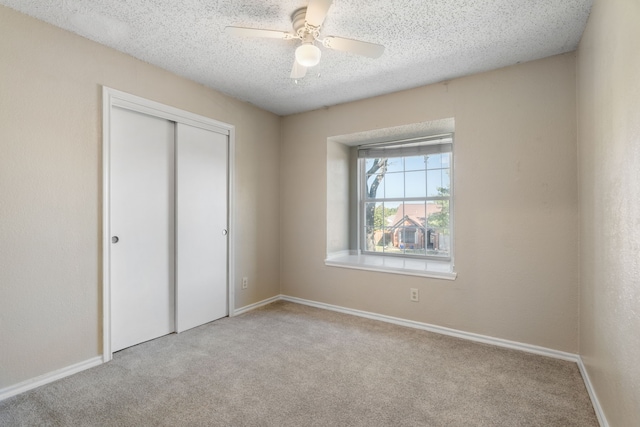 unfurnished bedroom with ceiling fan, light carpet, a closet, and a textured ceiling