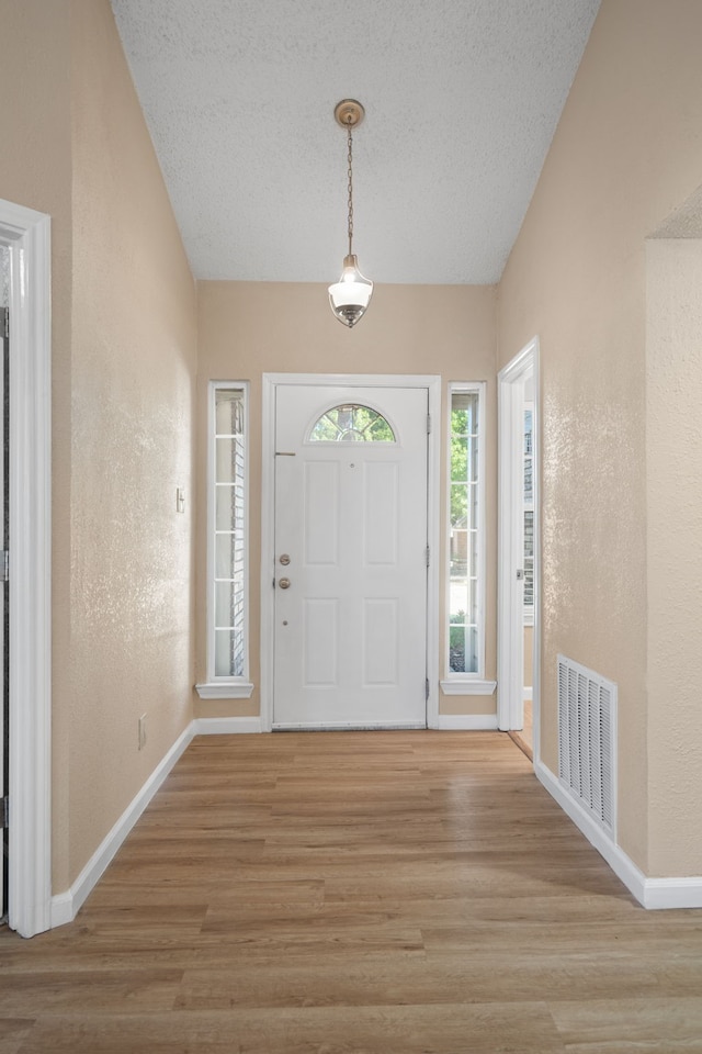 foyer entrance featuring a textured ceiling and light hardwood / wood-style flooring