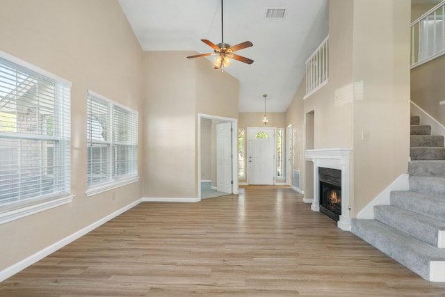 unfurnished living room featuring high vaulted ceiling, plenty of natural light, and light hardwood / wood-style flooring