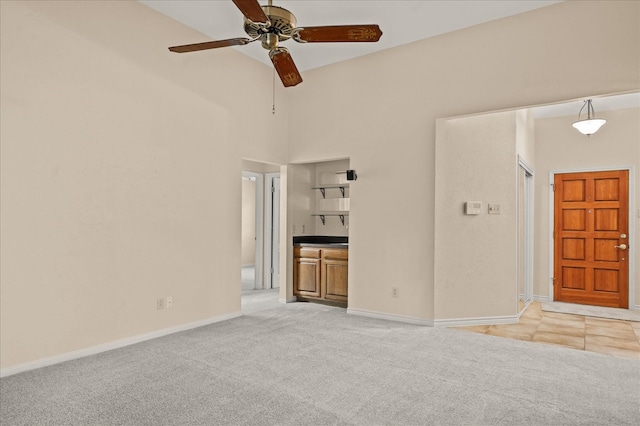 unfurnished living room with a high ceiling, ceiling fan, and light carpet