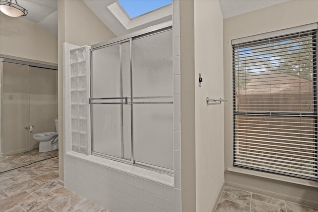 bathroom featuring walk in shower, toilet, and lofted ceiling with skylight