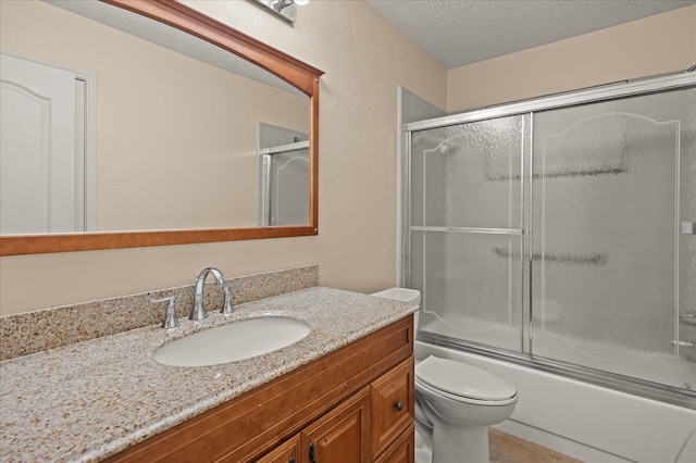 full bathroom featuring toilet, vanity, a textured ceiling, and shower / bath combination with glass door