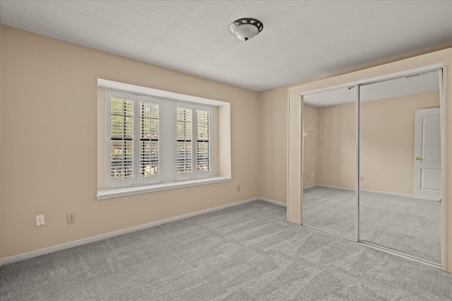 unfurnished bedroom with a closet, a textured ceiling, and light colored carpet