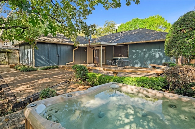 back of property with a hot tub and a patio