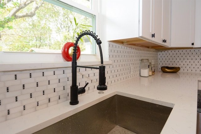 details with light stone counters, backsplash, and white cabinets