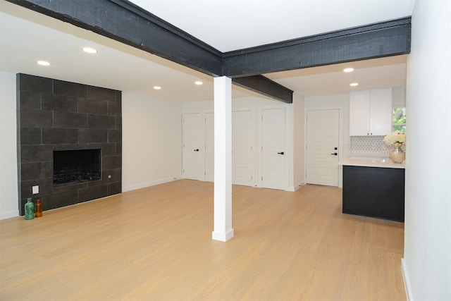 basement with light hardwood / wood-style floors and a tiled fireplace