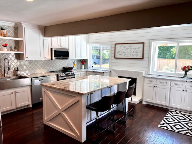 kitchen with stainless steel appliances, dark hardwood / wood-style flooring, light stone counters, white cabinets, and sink