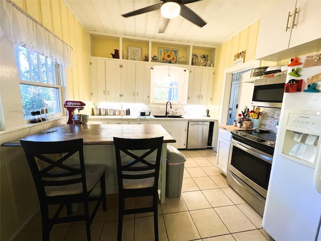 kitchen featuring a breakfast bar, white cabinetry, sink, and stainless steel appliances