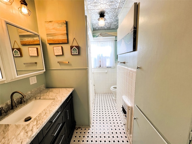 bathroom with vanity, toilet, and tile walls