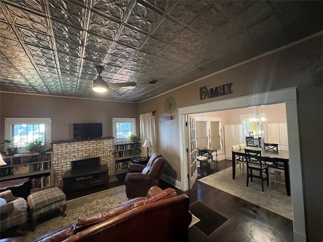 living room featuring a fireplace, dark hardwood / wood-style flooring, and ceiling fan with notable chandelier