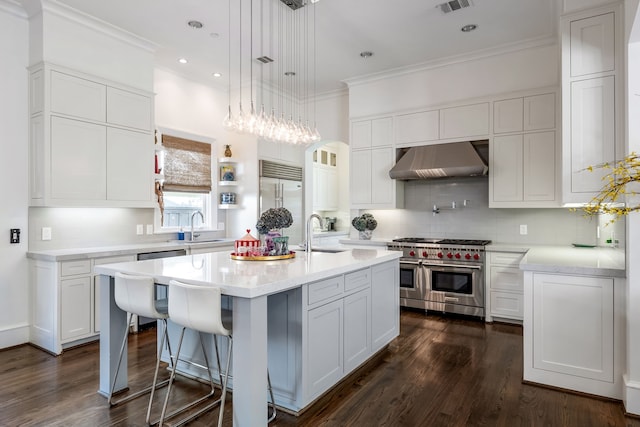 kitchen featuring a center island with sink, white cabinetry, wall chimney exhaust hood, and high quality appliances