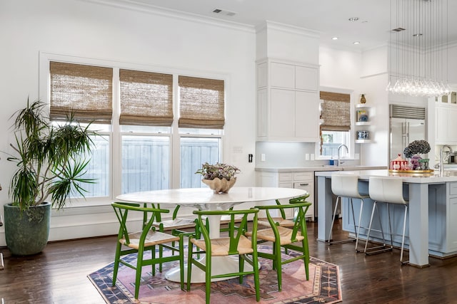 kitchen with white cabinets, ornamental molding, dark hardwood / wood-style floors, a kitchen island, and appliances with stainless steel finishes