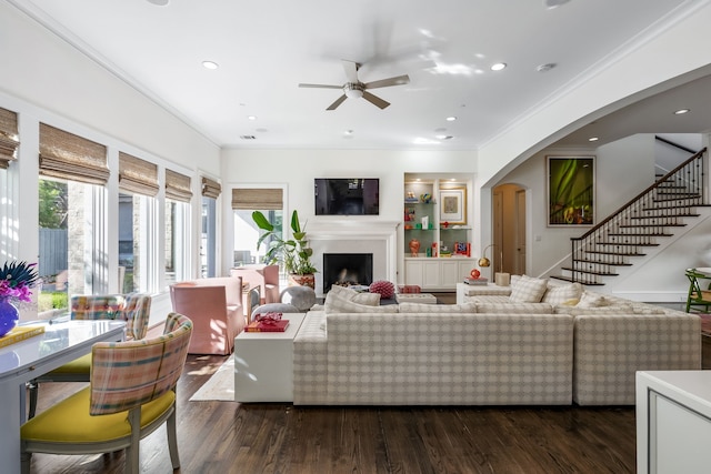 living room featuring dark wood-type flooring, ceiling fan, and crown molding