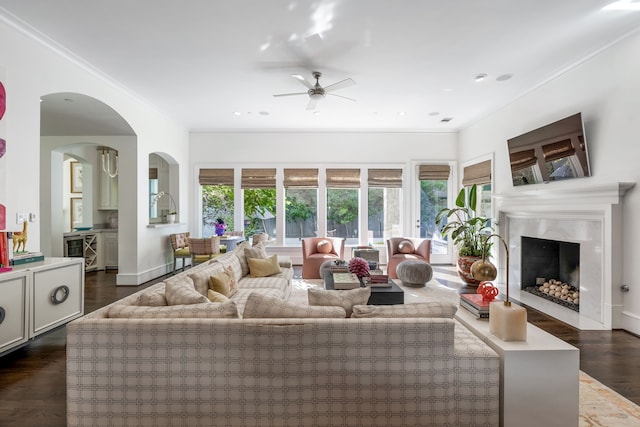 living room featuring dark wood-type flooring, ornamental molding, ceiling fan, a high end fireplace, and wine cooler