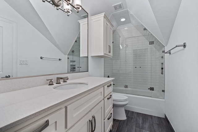 full bathroom with combined bath / shower with glass door, a chandelier, vanity, toilet, and vaulted ceiling