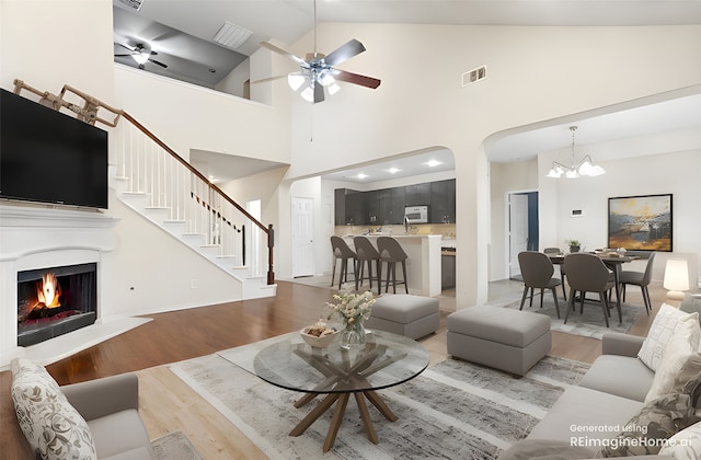 living area featuring light wood finished floors, a warm lit fireplace, stairway, and visible vents