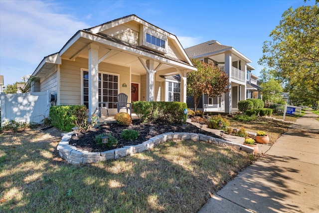 view of front facade with a balcony, a front yard, and covered porch